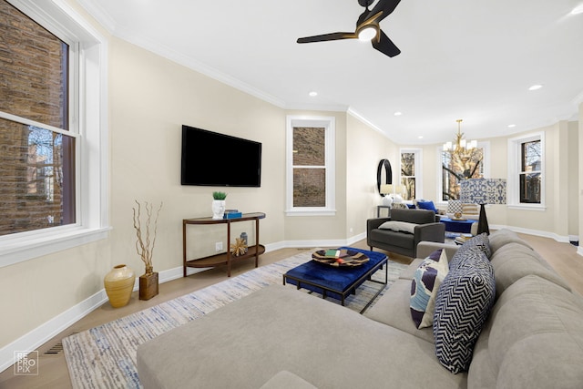 living room featuring ceiling fan with notable chandelier, crown molding, baseboards, and wood finished floors