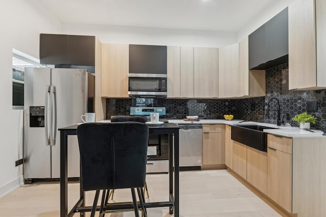 kitchen featuring backsplash, sink, light hardwood / wood-style flooring, light brown cabinetry, and appliances with stainless steel finishes