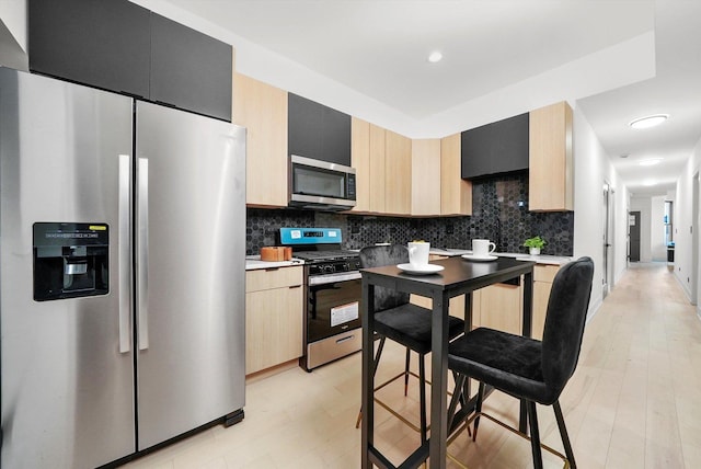 kitchen featuring light brown cabinets, stainless steel appliances, light hardwood / wood-style flooring, and tasteful backsplash