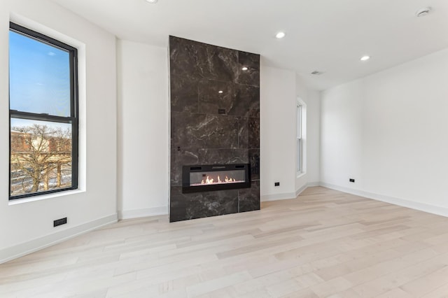 unfurnished living room with light hardwood / wood-style floors and a tiled fireplace