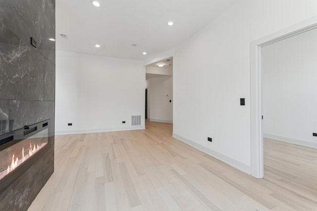 unfurnished living room featuring a fireplace and light hardwood / wood-style floors