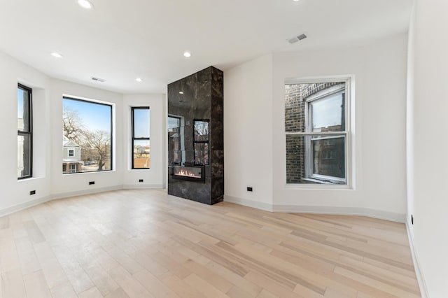 unfurnished living room with light wood-type flooring and a premium fireplace