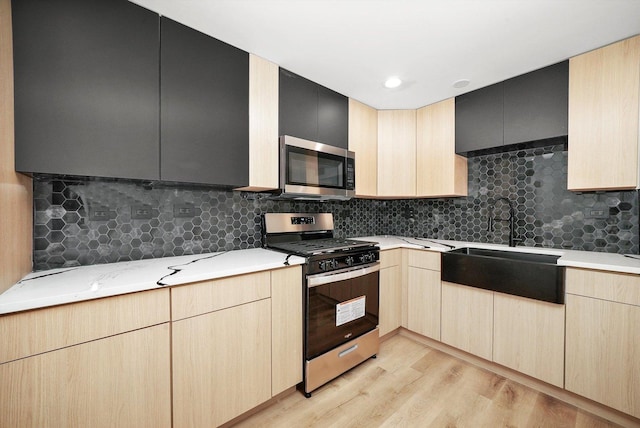 kitchen with backsplash, stainless steel appliances, light brown cabinetry, and light hardwood / wood-style flooring