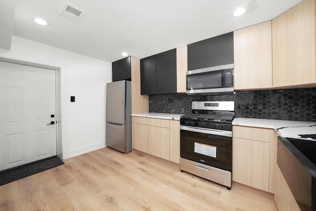 kitchen with decorative backsplash, appliances with stainless steel finishes, light brown cabinets, and light wood-type flooring