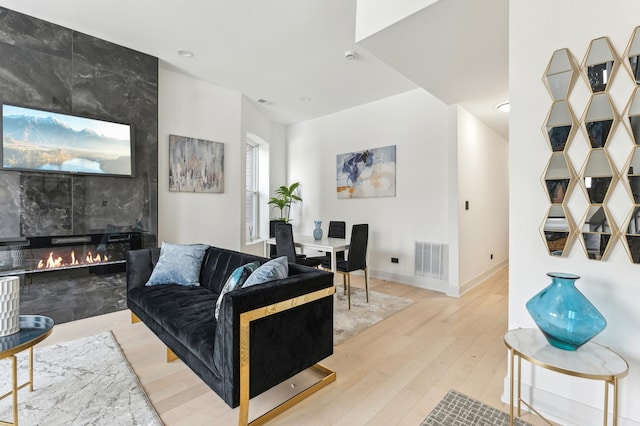 living room featuring a tile fireplace and light hardwood / wood-style flooring