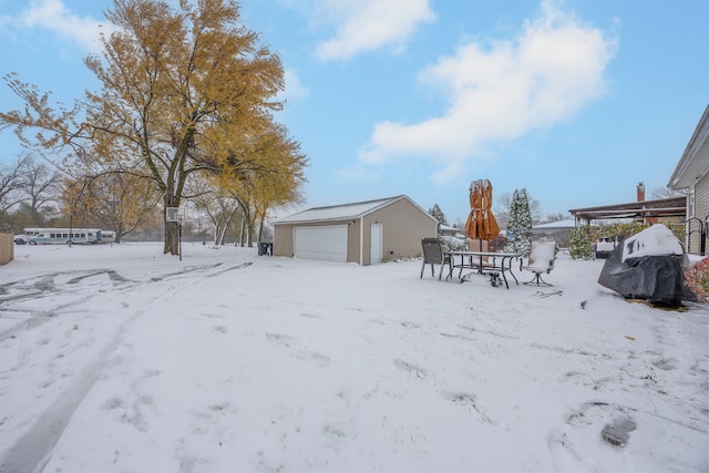 yard layered in snow featuring a garage and an outdoor structure