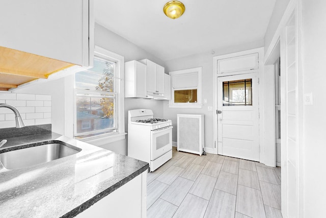 kitchen with radiator, sink, decorative backsplash, white cabinetry, and white range with gas cooktop