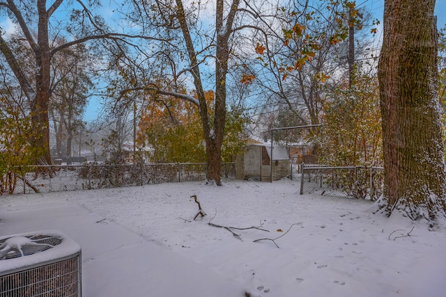 yard covered in snow featuring a shed and cooling unit