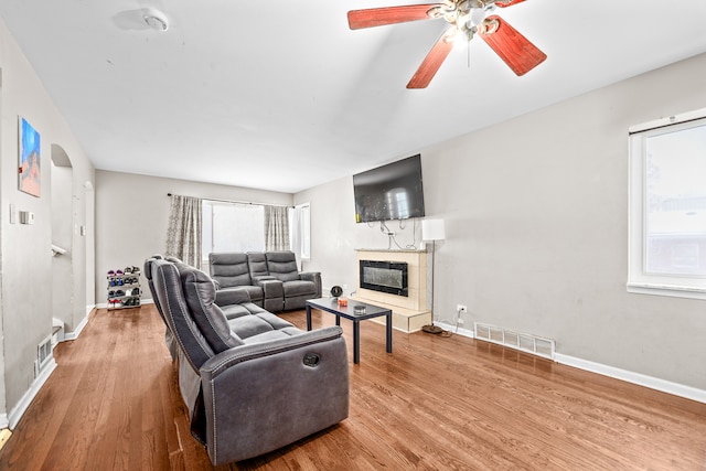 living room featuring a tile fireplace, hardwood / wood-style flooring, and ceiling fan