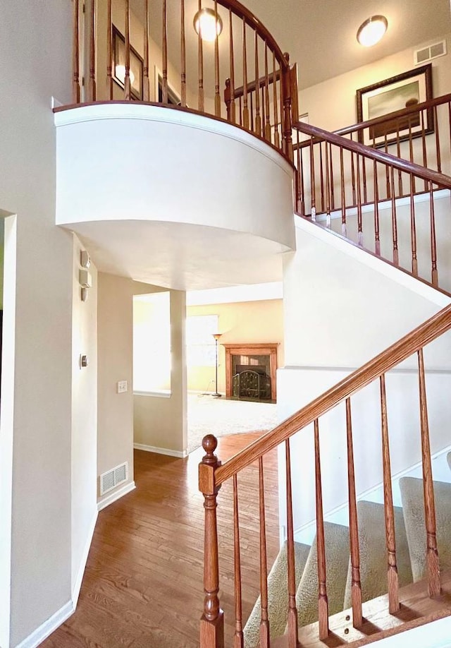 stairway with hardwood / wood-style flooring and a towering ceiling