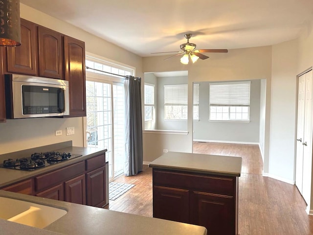 kitchen with gas stovetop, sink, ceiling fan, and light wood-type flooring