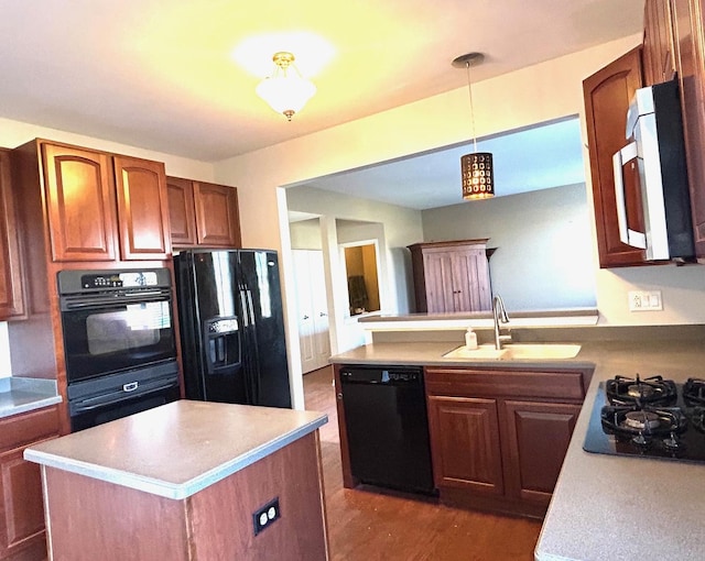 kitchen featuring decorative light fixtures, black appliances, sink, a center island, and kitchen peninsula