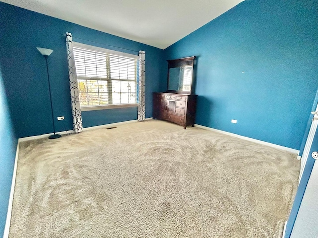 unfurnished bedroom featuring vaulted ceiling and carpet flooring