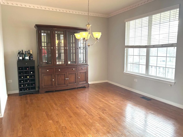 unfurnished dining area with a notable chandelier and wood-type flooring