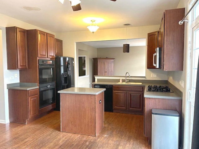 kitchen with sink, hanging light fixtures, a center island, wood-type flooring, and black appliances