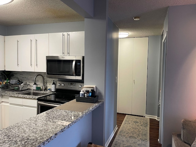 kitchen with white cabinets, light stone countertops, a textured ceiling, and appliances with stainless steel finishes