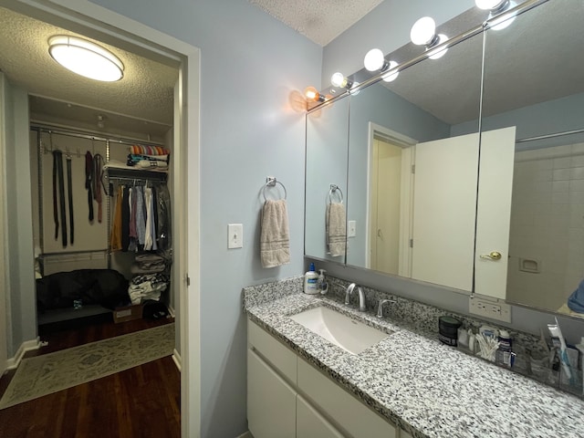 bathroom featuring hardwood / wood-style flooring, vanity, and a textured ceiling