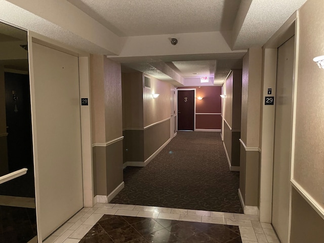 hall featuring a textured ceiling and light carpet