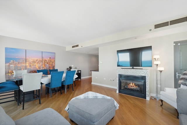 living room with a tile fireplace and light hardwood / wood-style floors