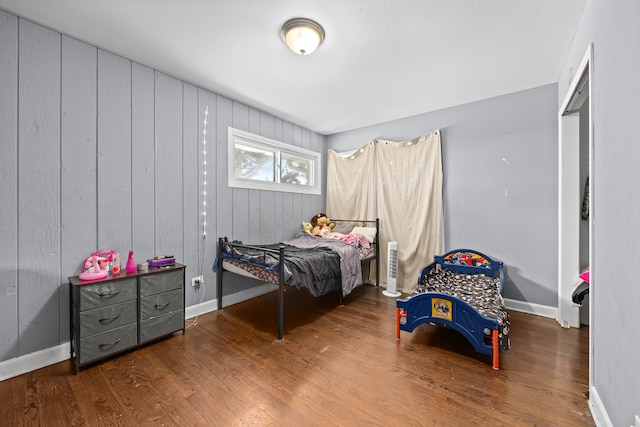 bedroom featuring wood walls and dark hardwood / wood-style floors