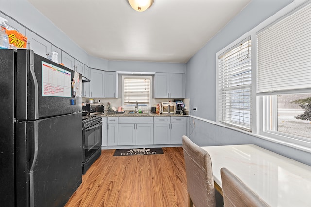 kitchen featuring a healthy amount of sunlight, sink, black appliances, and light hardwood / wood-style floors