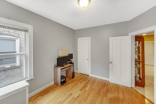 home office with radiator heating unit and light hardwood / wood-style floors