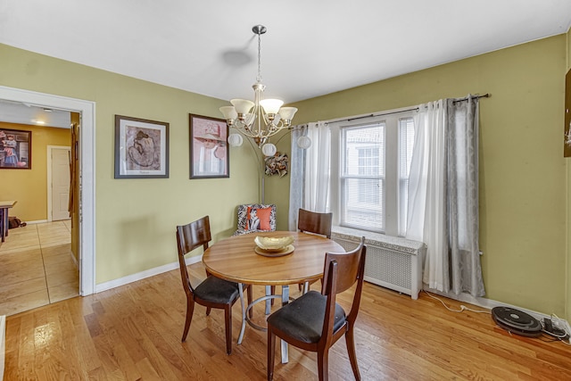 dining space with light wood-type flooring, radiator, and a chandelier