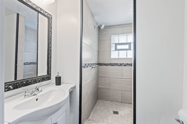 bathroom with tile patterned flooring, vanity, and tiled shower