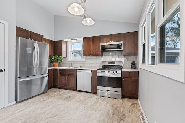 kitchen featuring appliances with stainless steel finishes, tasteful backsplash, vaulted ceiling, and hanging light fixtures