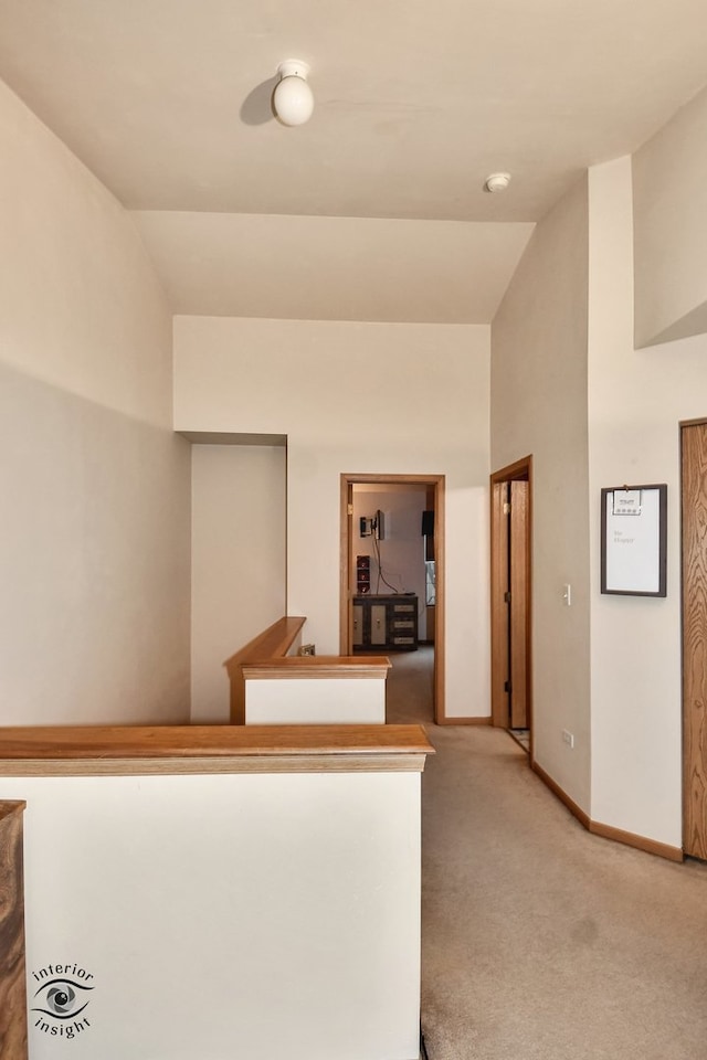 hall featuring light carpet and lofted ceiling