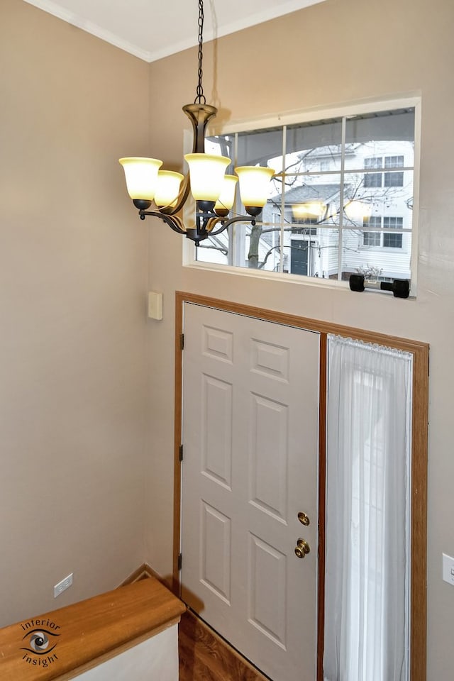 entrance foyer with a chandelier, ornamental molding, and dark wood-type flooring