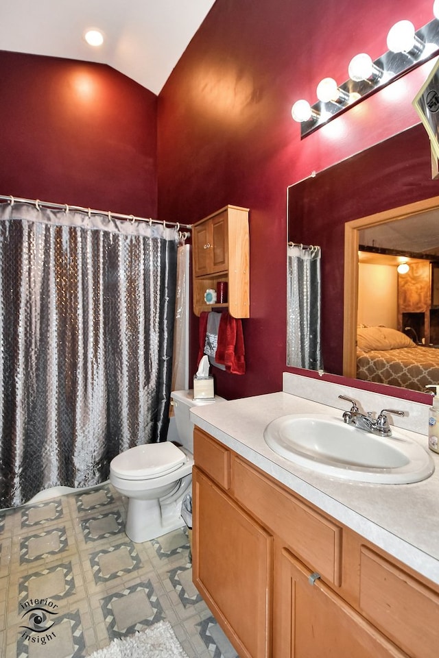 bathroom featuring vanity, vaulted ceiling, and toilet