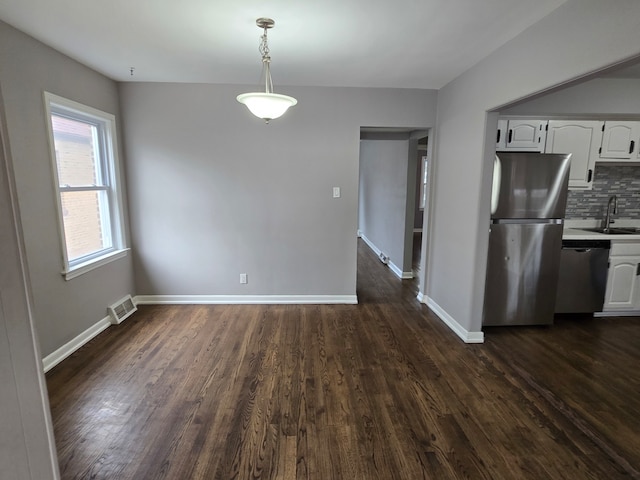 kitchen featuring appliances with stainless steel finishes, backsplash, pendant lighting, dark hardwood / wood-style floors, and white cabinetry