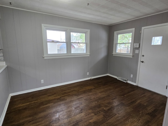 entrance foyer with a wealth of natural light, dark hardwood / wood-style floors, and ornamental molding