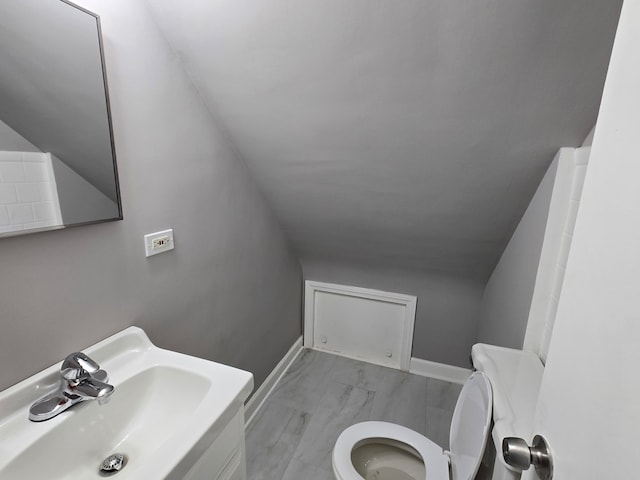 bathroom with toilet, lofted ceiling, and sink