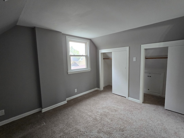 unfurnished bedroom with carpet floors and vaulted ceiling