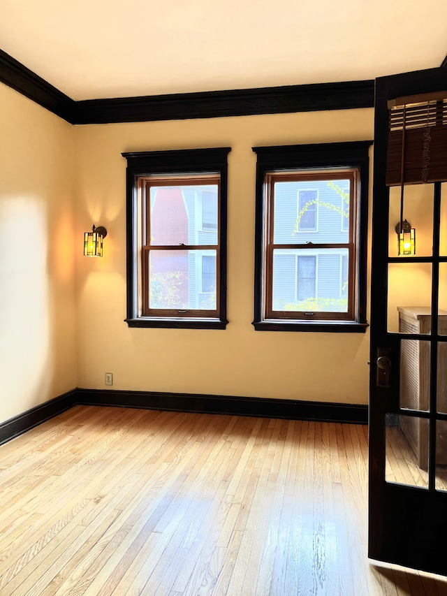 unfurnished room with crown molding and light wood-type flooring