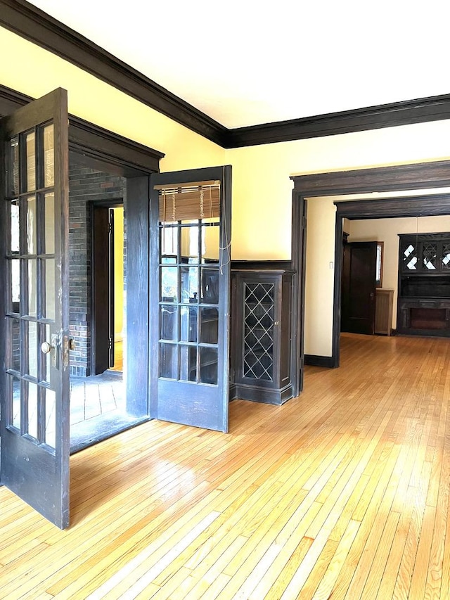 spare room featuring a healthy amount of sunlight, hardwood / wood-style flooring, french doors, and ornamental molding