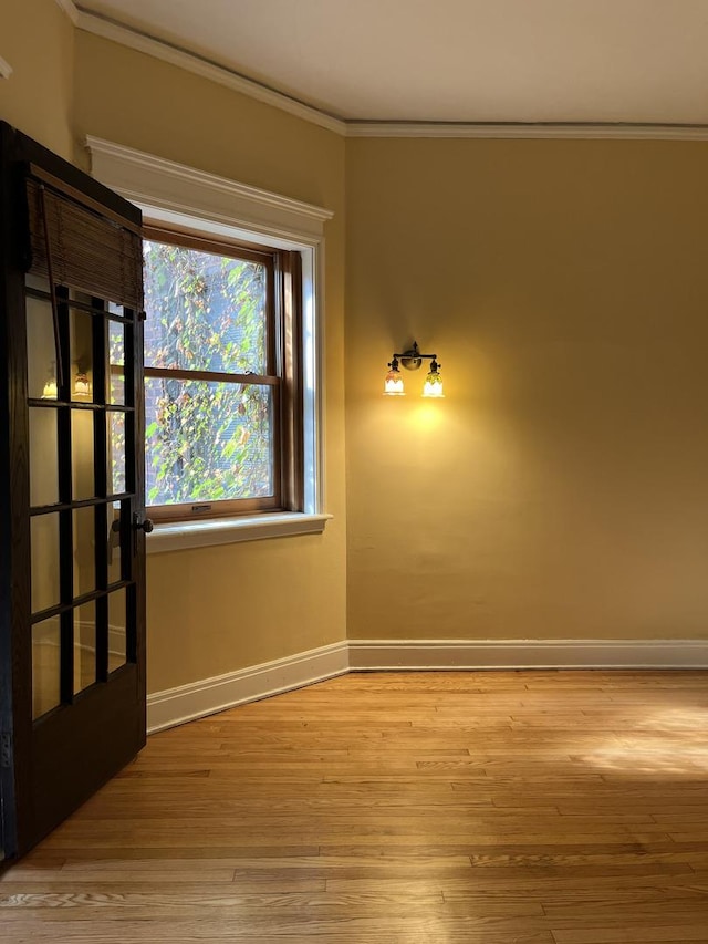 empty room with french doors, light hardwood / wood-style flooring, and crown molding