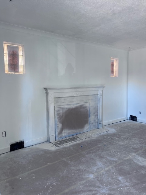 unfurnished living room with ornamental molding and a textured ceiling