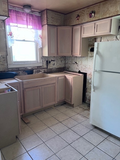 kitchen with white refrigerator, light tile patterned floors, and sink