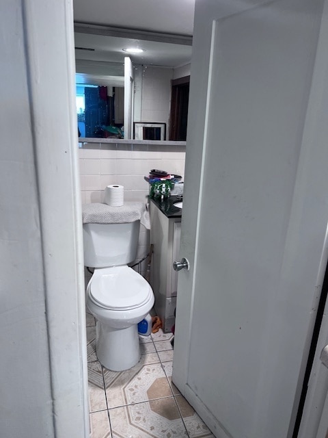 bathroom featuring tile patterned flooring, backsplash, toilet, and tile walls