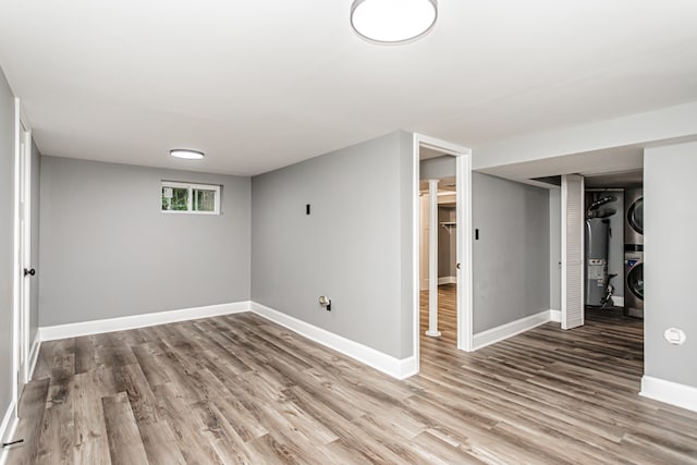 basement with hardwood / wood-style flooring, stacked washer / drying machine, and water heater