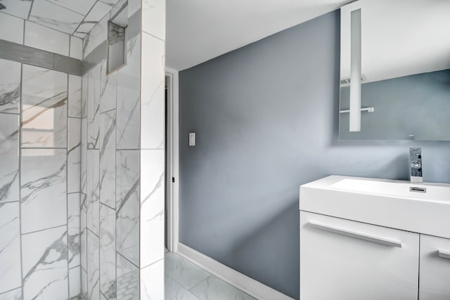 bathroom with a tile shower and vanity