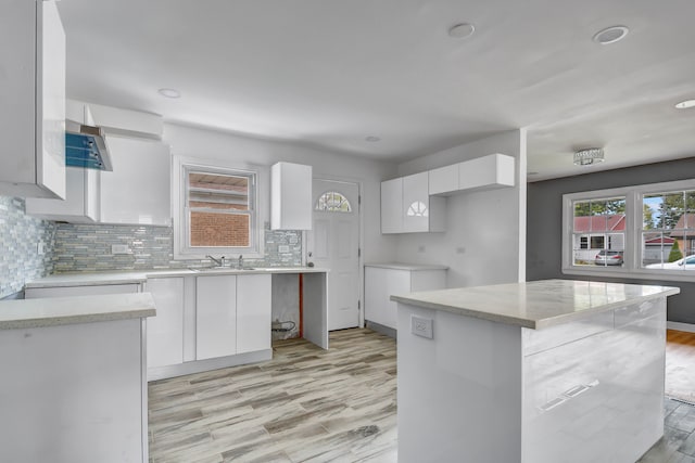 kitchen with white cabinets, decorative backsplash, a center island, and light hardwood / wood-style floors