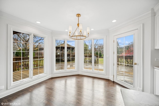 unfurnished dining area featuring dark hardwood / wood-style floors, ornamental molding, and a chandelier