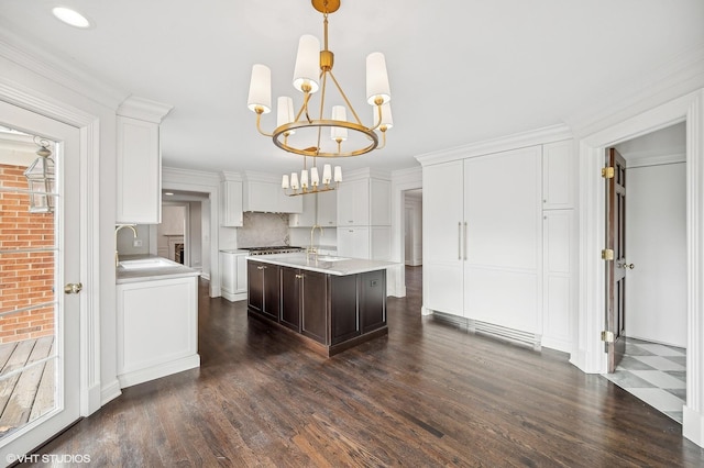 kitchen featuring pendant lighting, white cabinets, an island with sink, and dark wood-type flooring