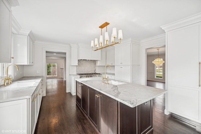 kitchen featuring a center island with sink, a chandelier, sink, and dark wood-type flooring