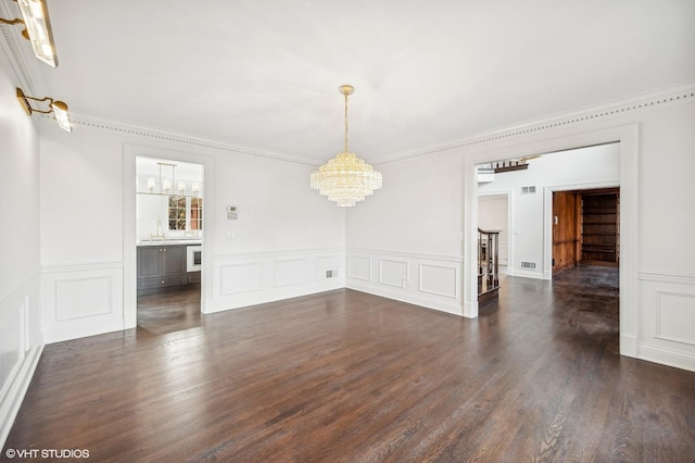 spare room featuring a chandelier, dark hardwood / wood-style floors, and ornamental molding