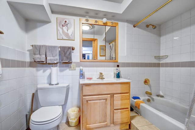 full bathroom featuring vanity, tile patterned flooring, tiled shower / bath combo, toilet, and tile walls